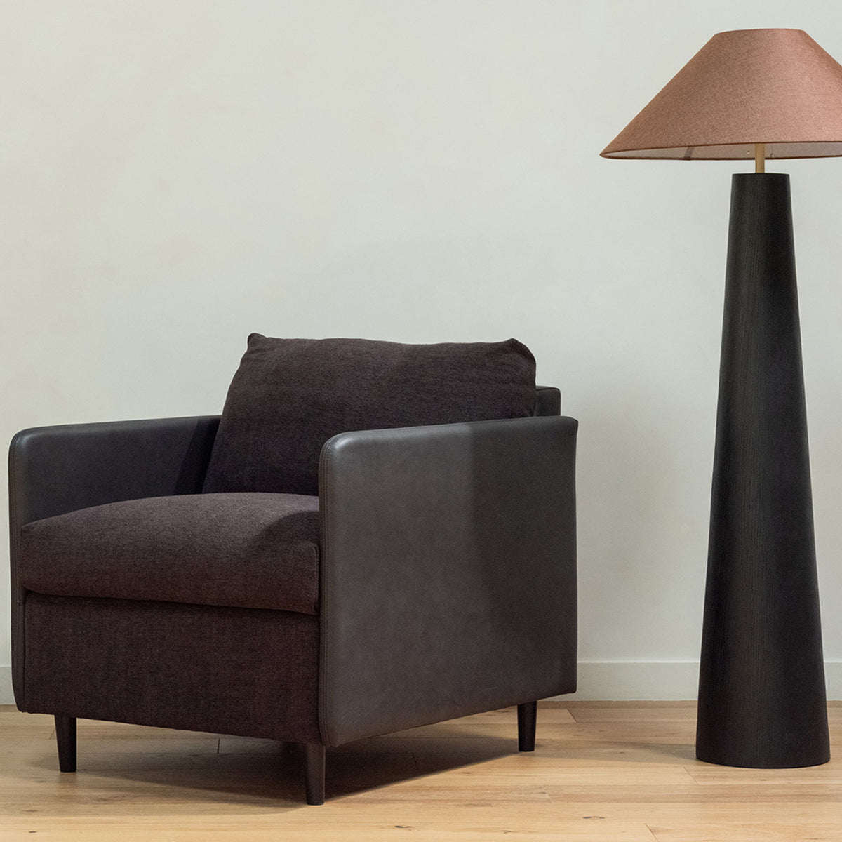 Warm black accent chair with wide arms, thick seat cushion, and tapered legs
