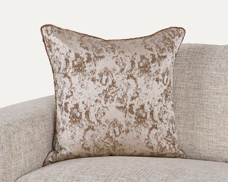 Textured throw pillow with mottled light beige pattern and piped edges, square shape