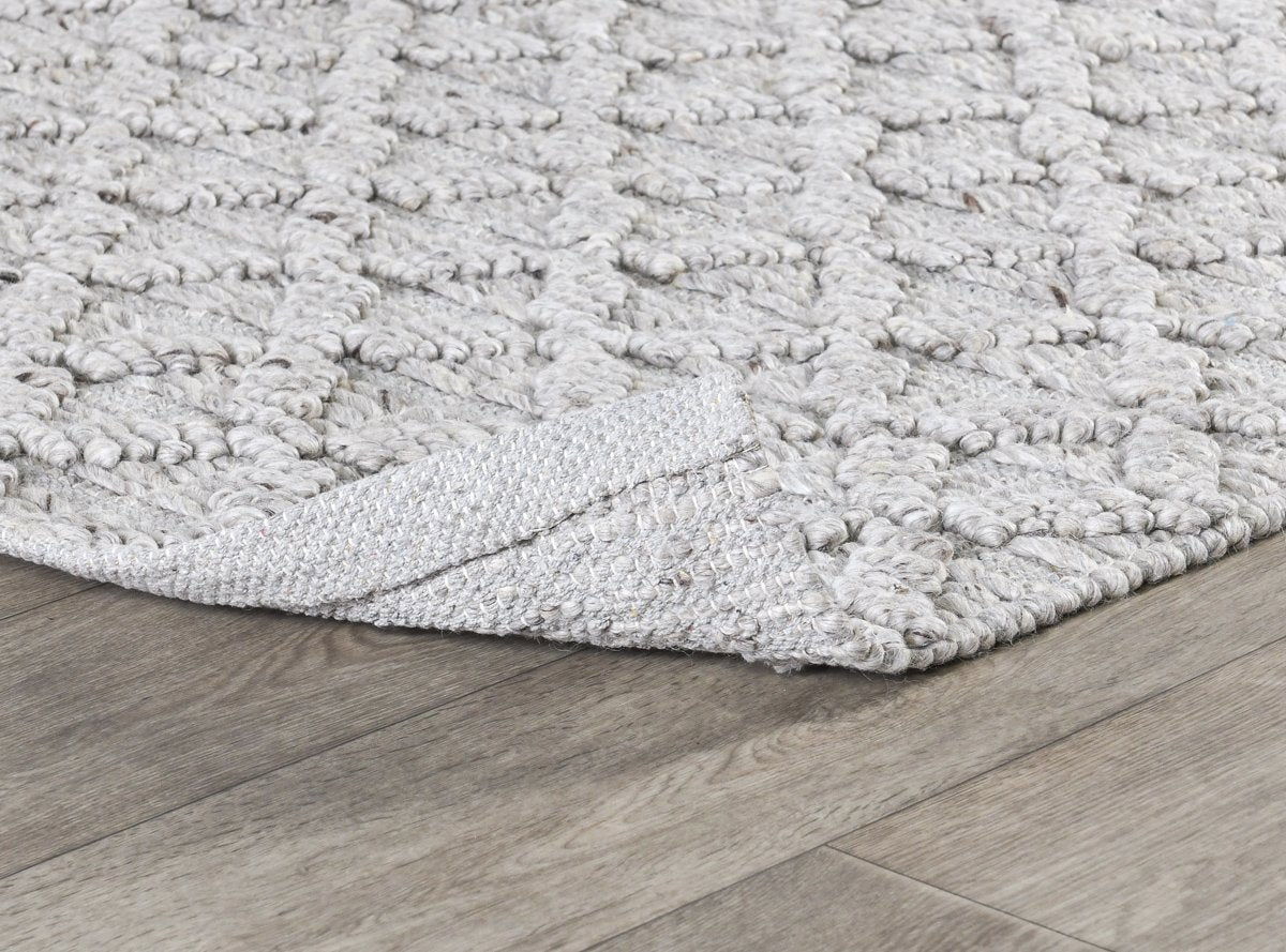 Ivory textured area rug with raised loop surface and low-profile woven edge.