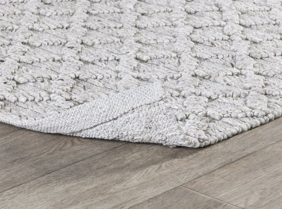 Ivory textured area rug with raised loop surface and low-profile woven edge.