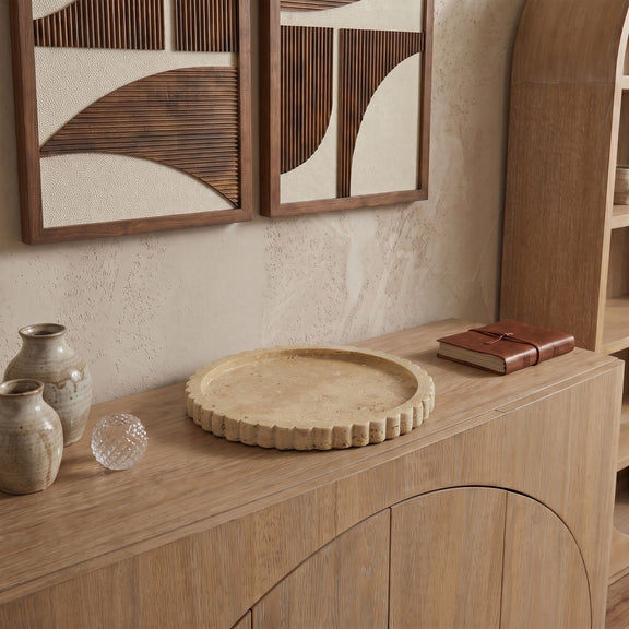 Travertine tray on wooden shelf with scalloped rim and circular top.
