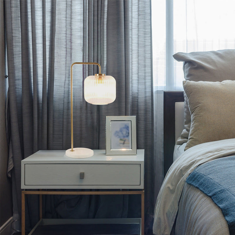 Gold table lamp with clear ribbed glass shade on round white marble base