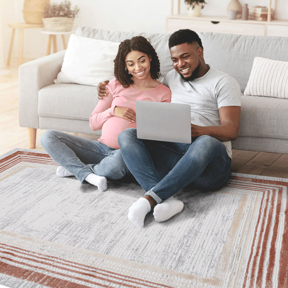 Rectangular ivory and brown bordered area rug with striped frame, partial corner view