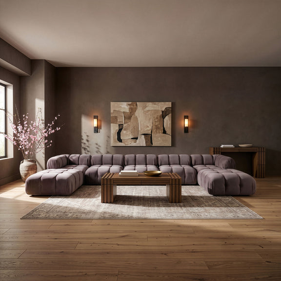 Gray modular sectional sofa with tufted cushions, rounded seat modules, and ottoman pieces