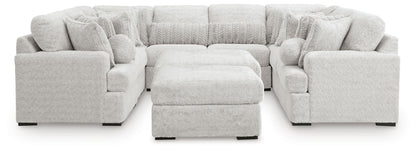 Light gray cuddle plush sectional sofa with central ottoman and rounded arm seat blocks