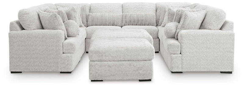 Light gray cuddle plush sectional sofa with central ottoman and rounded arm seat blocks