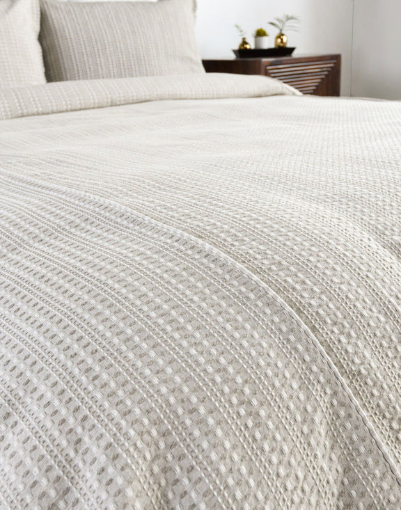 Closeup of white textured woven pillow sham with vertical stripe stitching