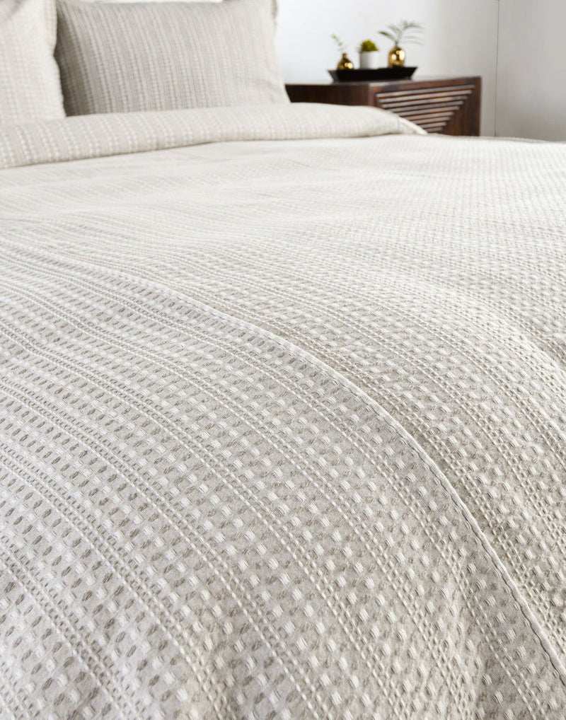 Closeup of white textured woven pillow sham with vertical stripe stitching