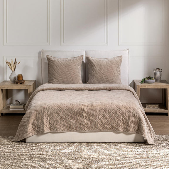 Quilt in light beige with textured weave and matching pillows on a bed