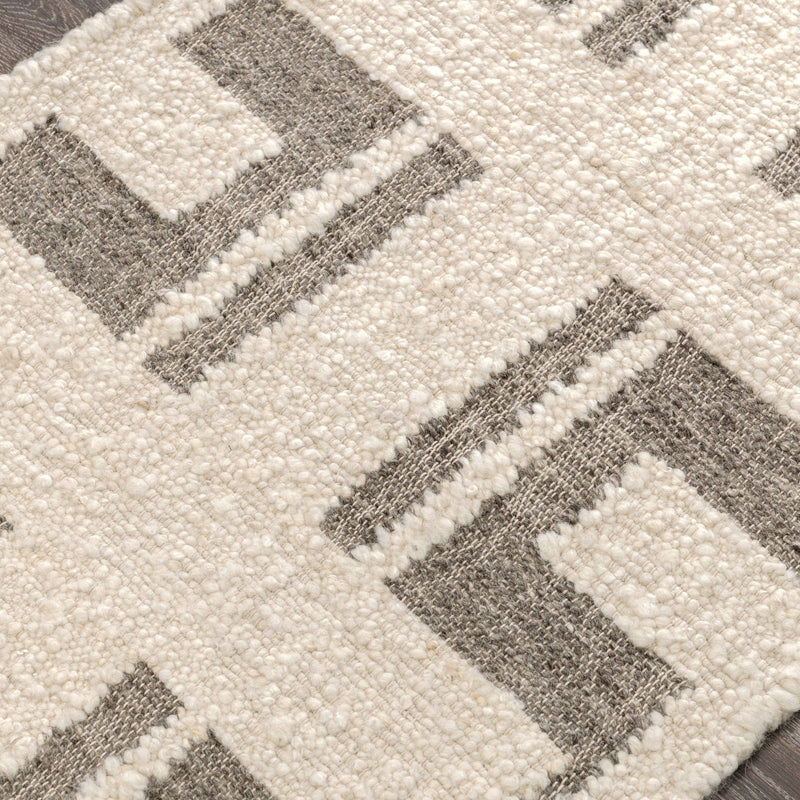 Close-up of ivory rug with textured dots and gray geometric stripe inlays