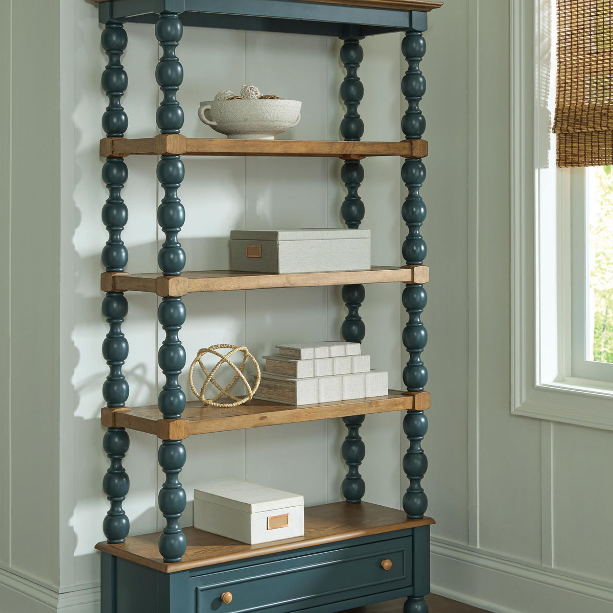 Wood and teal bookcase with open shelves and lower drawer, styled with decor on top