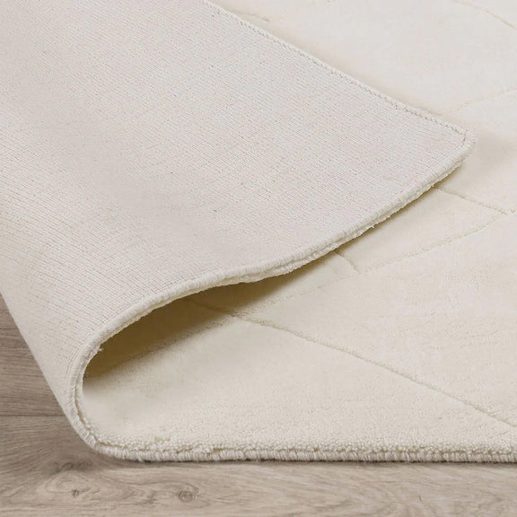 Ivory wool rug corner detail with stitched binding and short fringe