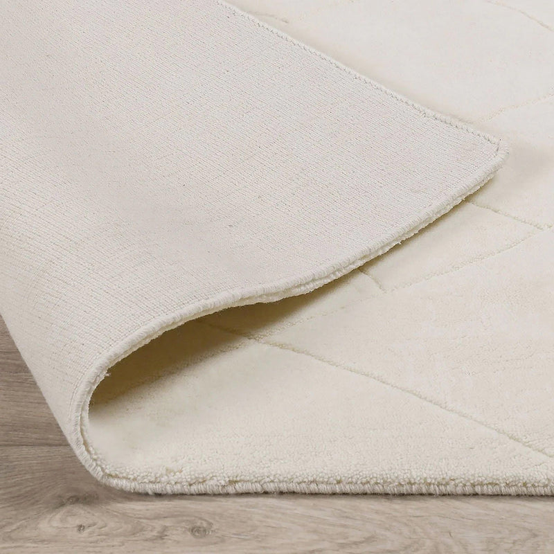 Ivory wool rug corner detail with stitched binding and short fringe