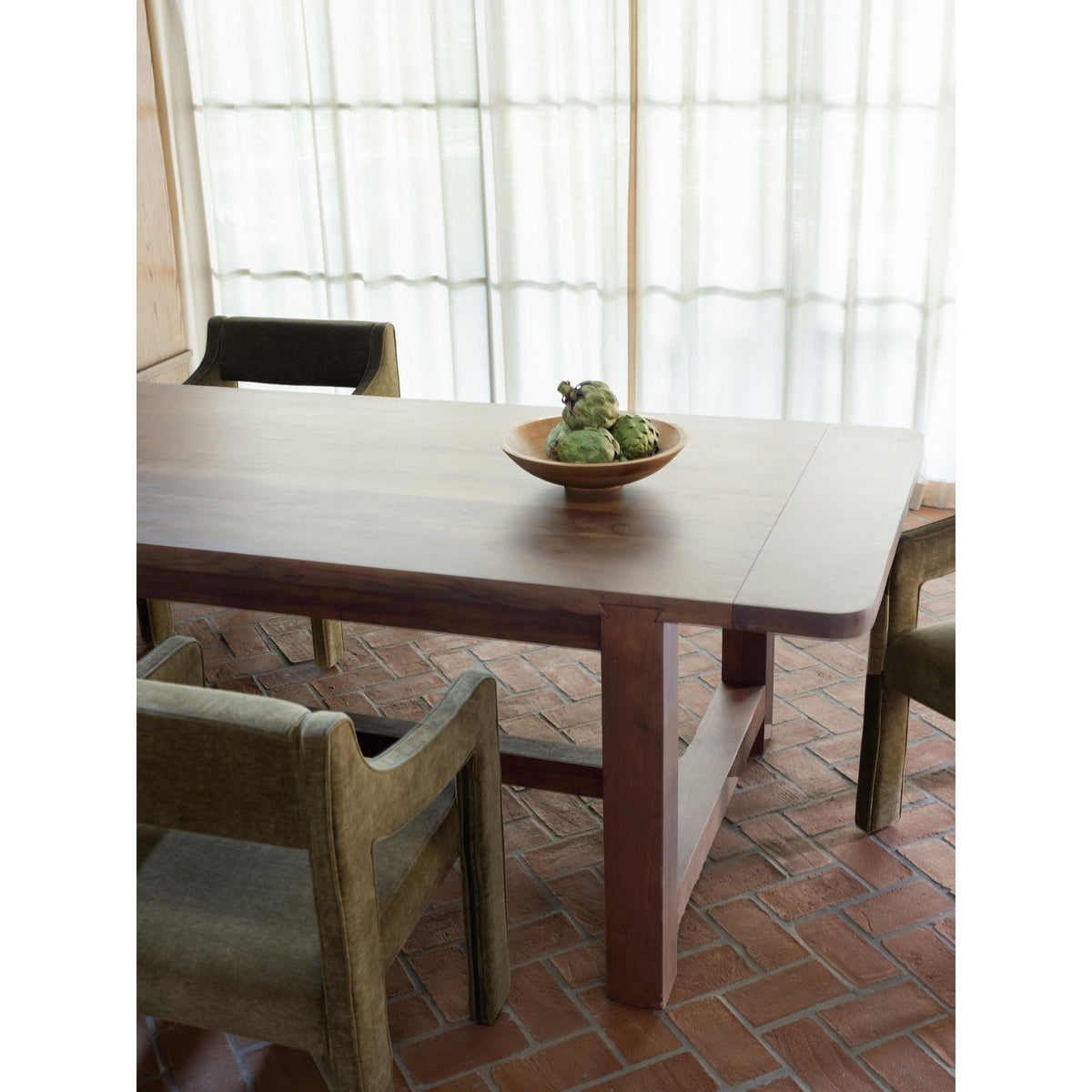 Warm brown dining table with beveled edges, centered leg, and two dining chairs.