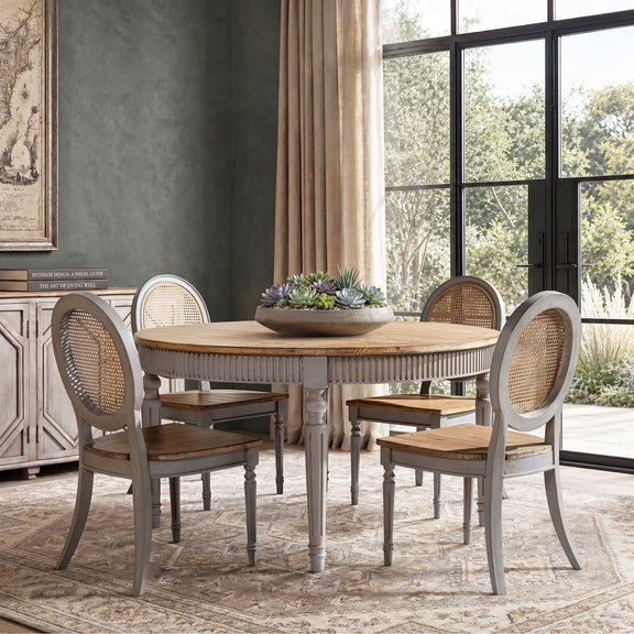 Round dining table with light wood top and ridged apron, centerpiece on tabletop