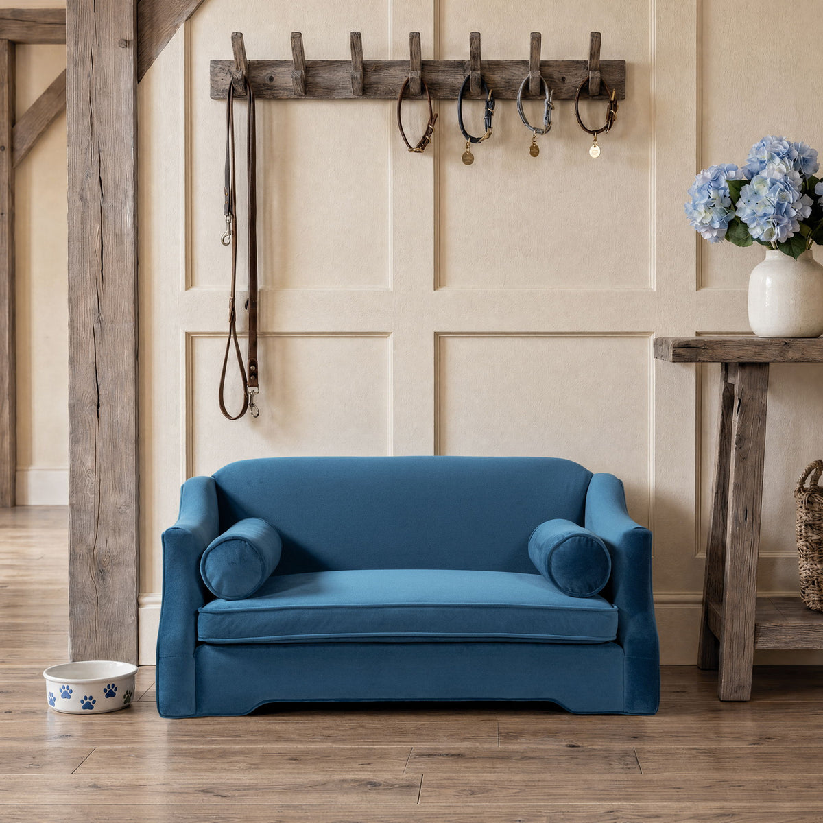 Blue dog sofa bed with plush upholstery, low back, and two rounded arm bolster pillows