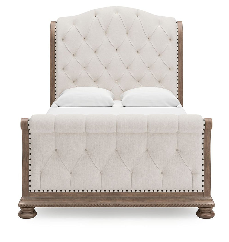 Cream tufted sleigh bed with button details and nailhead-trimmed side rails