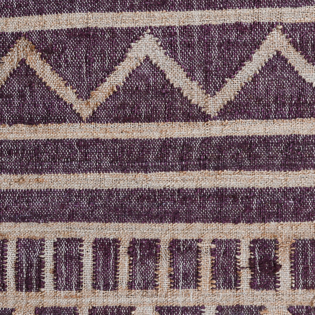 Close-up distressed rug with purple diamond pattern, cream stripes, and fringe