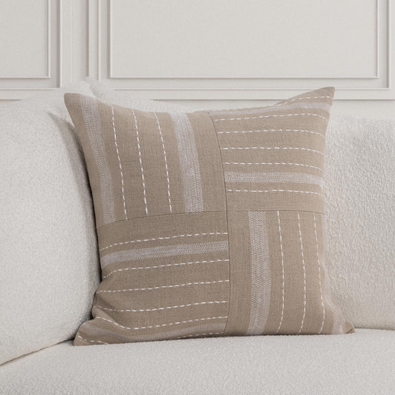 Natural origin pillow on sofa cushion, striped patchwork front with dotted stitch detailing