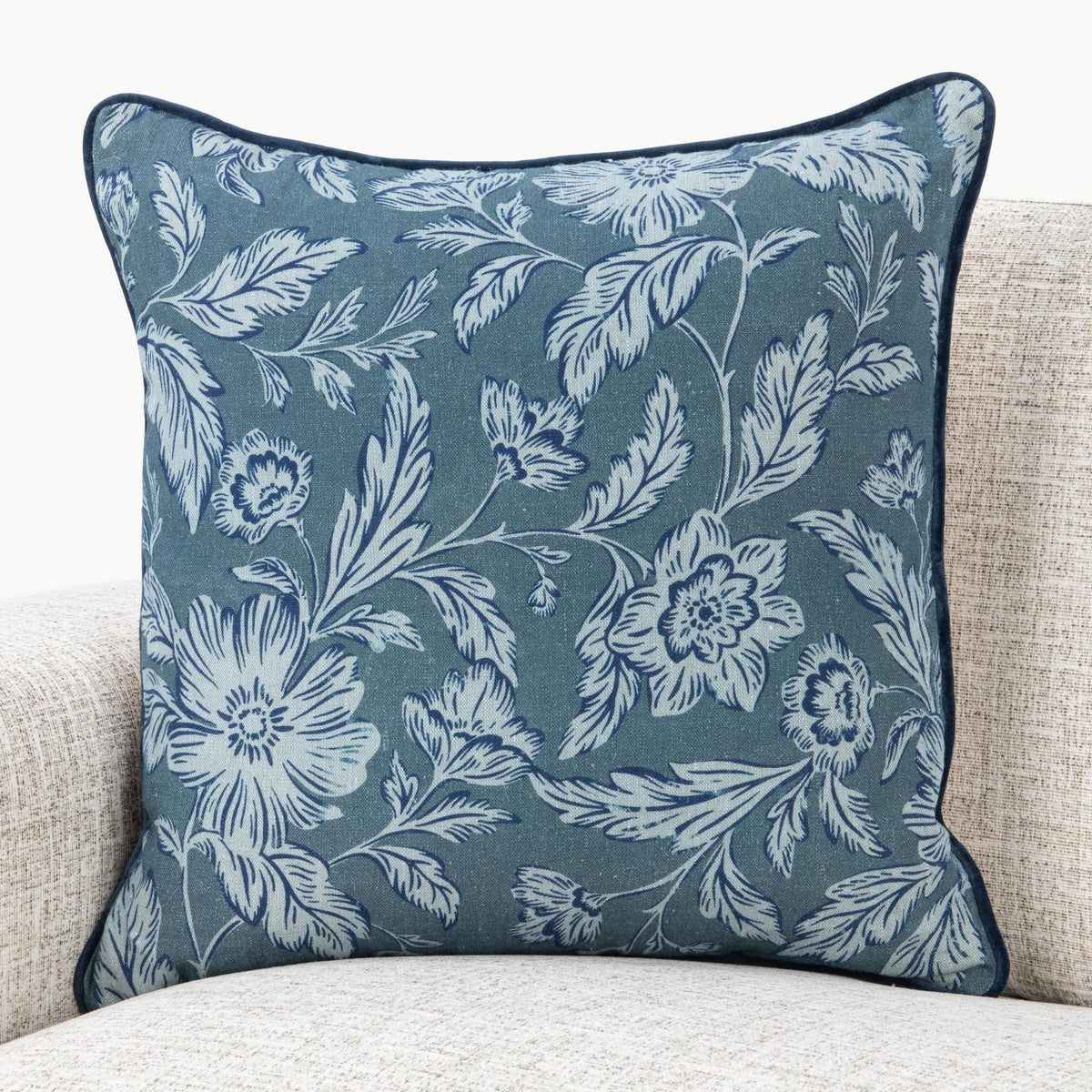 Blue floral square pillow with white botanical pattern and dark edge piping