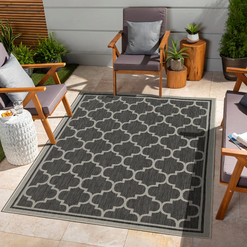 Dark gray polypropylene area rug with repeating quatrefoil pattern and bordered edges