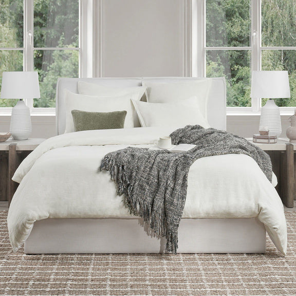 Natural linen-look duvet with white pillow shams and a dark gray fringe throw