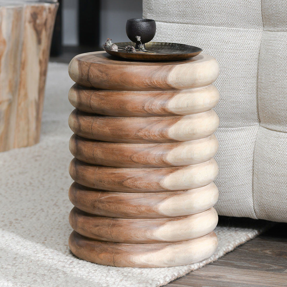 Natural round end table with stacked ring base and wood grain, top styled with decor