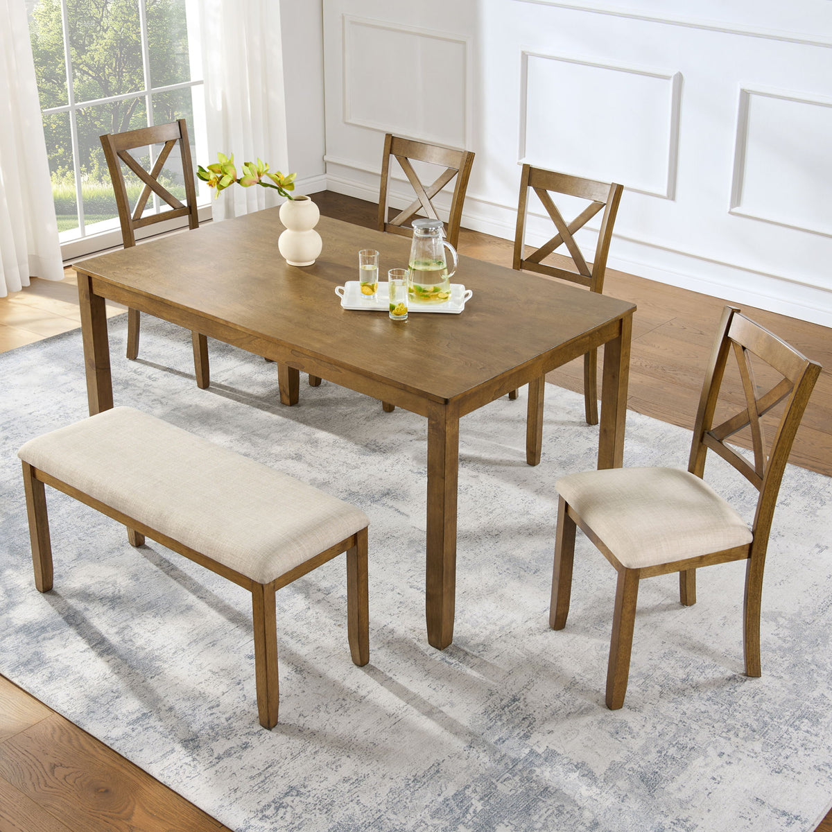 Dining table set with upholstered bench and four cross-back chairs on light wood.