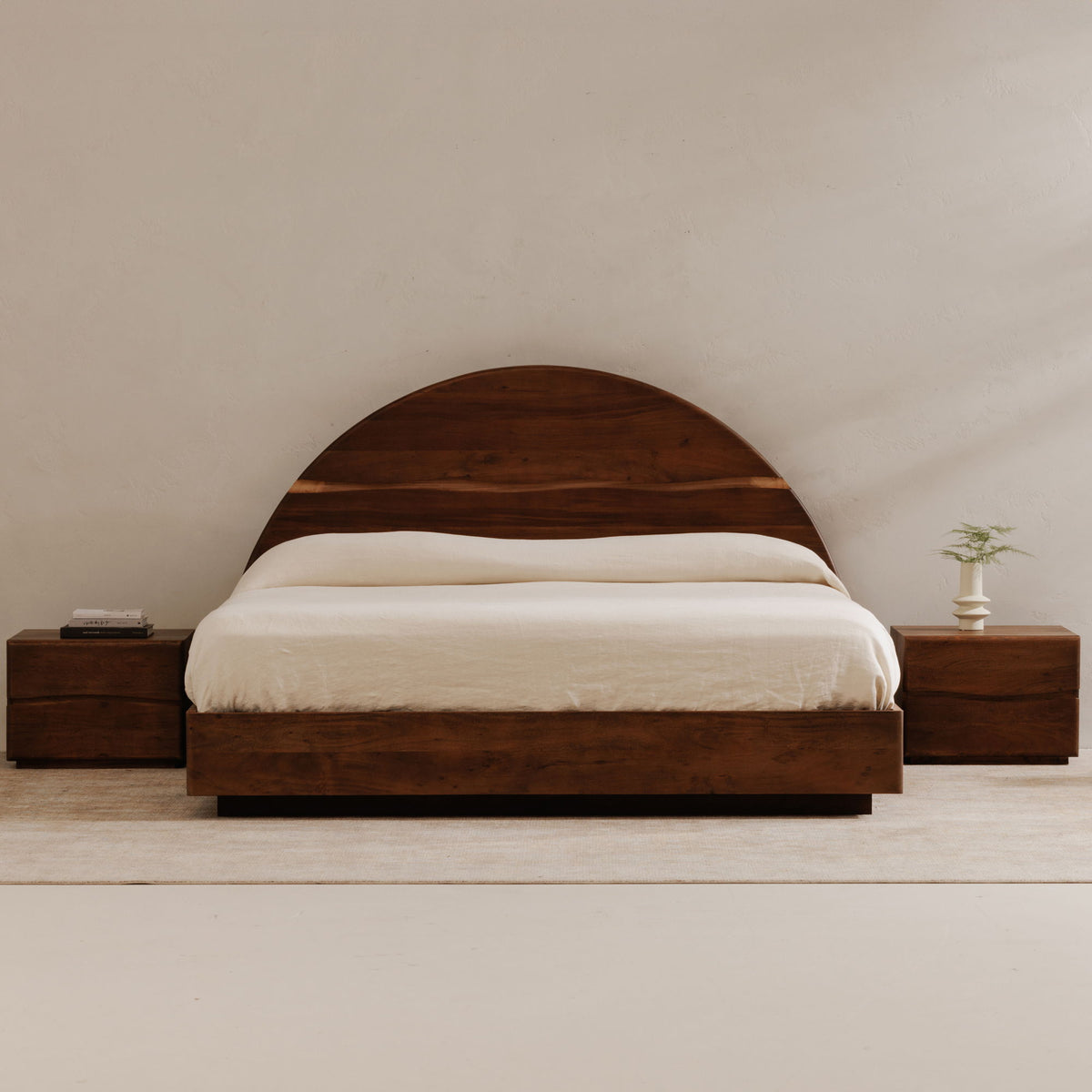 Brown queen bed with curved headboard, white bedding, and matching nightstands