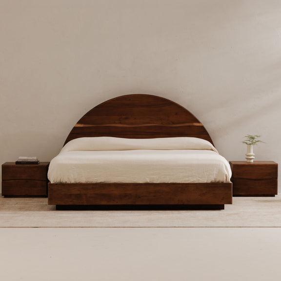 Brown queen bed with curved headboard, white bedding, and matching nightstands