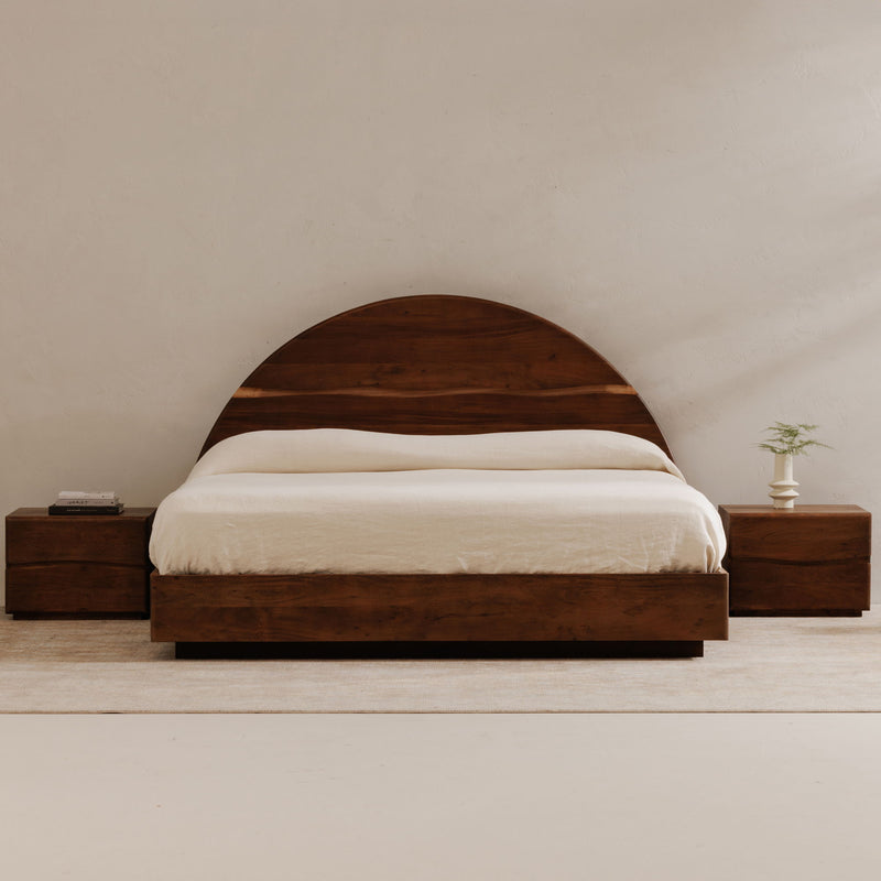 Brown queen bed with curved headboard, white bedding, and matching nightstands