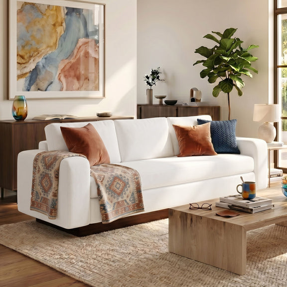 White 3-seater sofa with decorative pillows and folded throw blanket