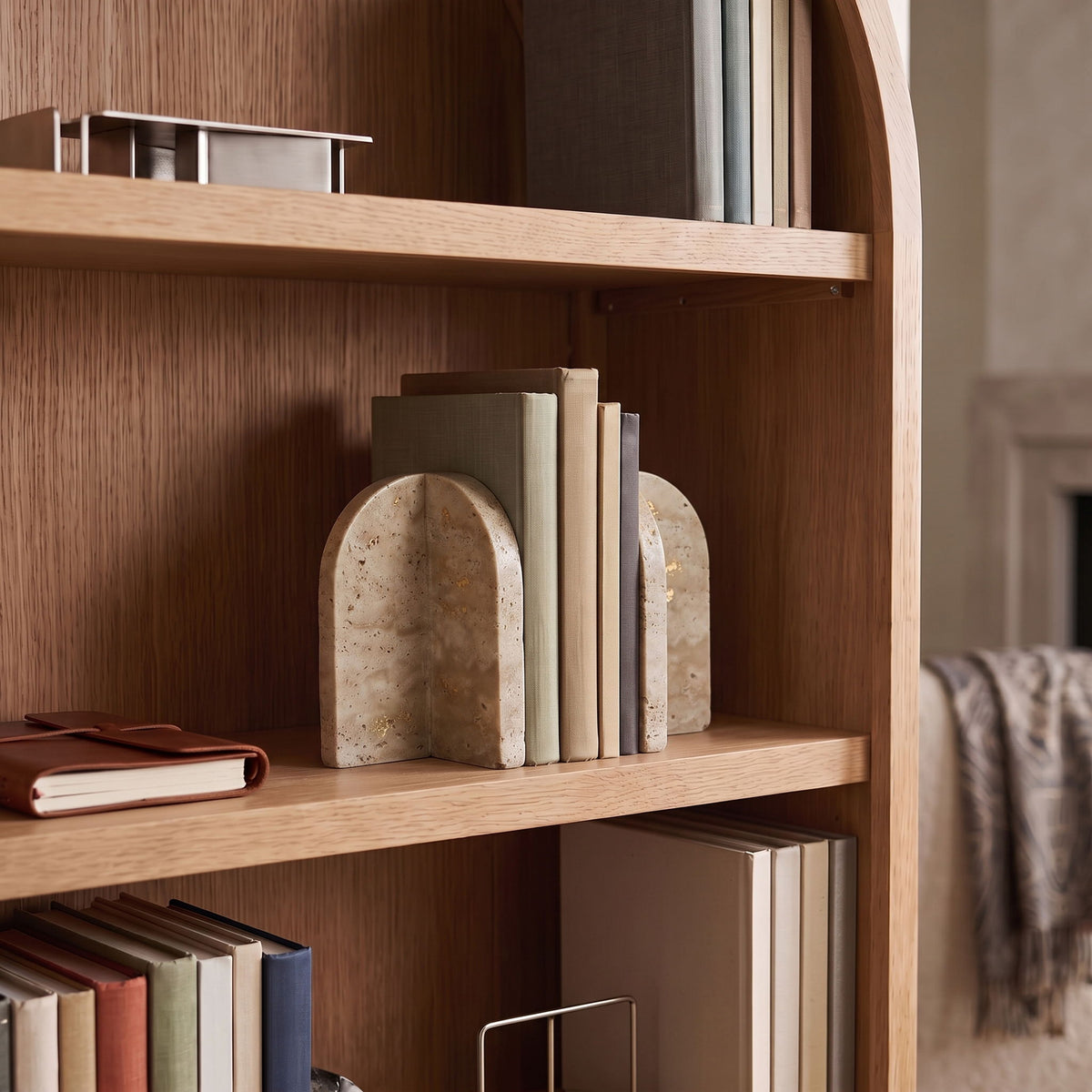 Travertine marble bookends on wooden shelf, upright arched bases holding books
