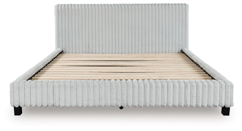 Light gray upholstered bed frame with ribbed headboard and base, neatly fitted mattress.