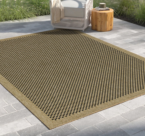 Light brown indoor-outdoor area rug with black-and-brown checkered pattern border