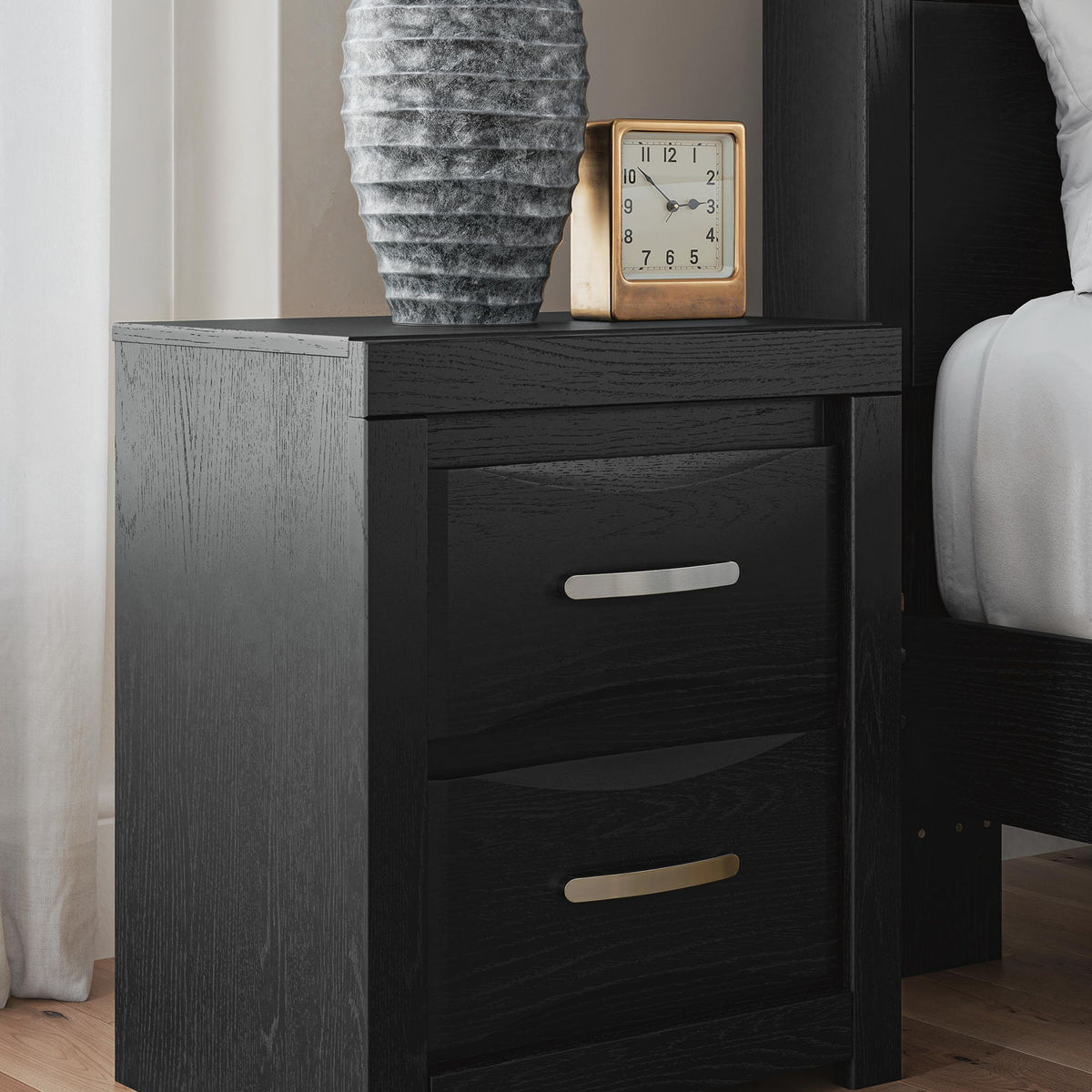 Black two-drawer nightstand with silver bar handles, styled with tabletop decor.