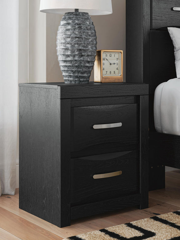 Black two-drawer nightstand with silver bar handles, styled with tabletop decor.