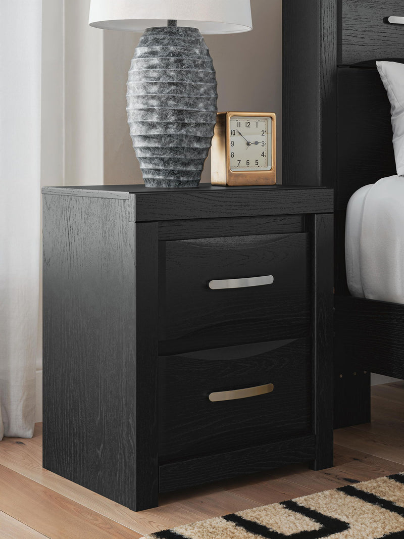 Black two-drawer nightstand with silver bar handles, styled with tabletop decor.