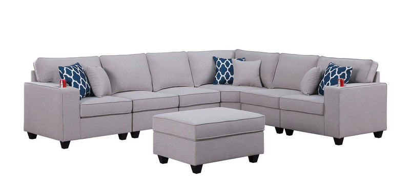 Gray sectional sofa with ottoman centerpiece and blue patterned accent pillows, wide view