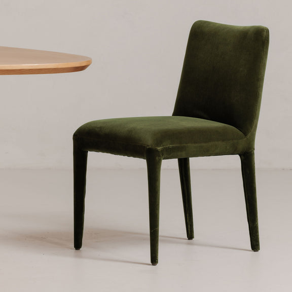Green velvet dining chair with tall square back, padded seat, tapered legs