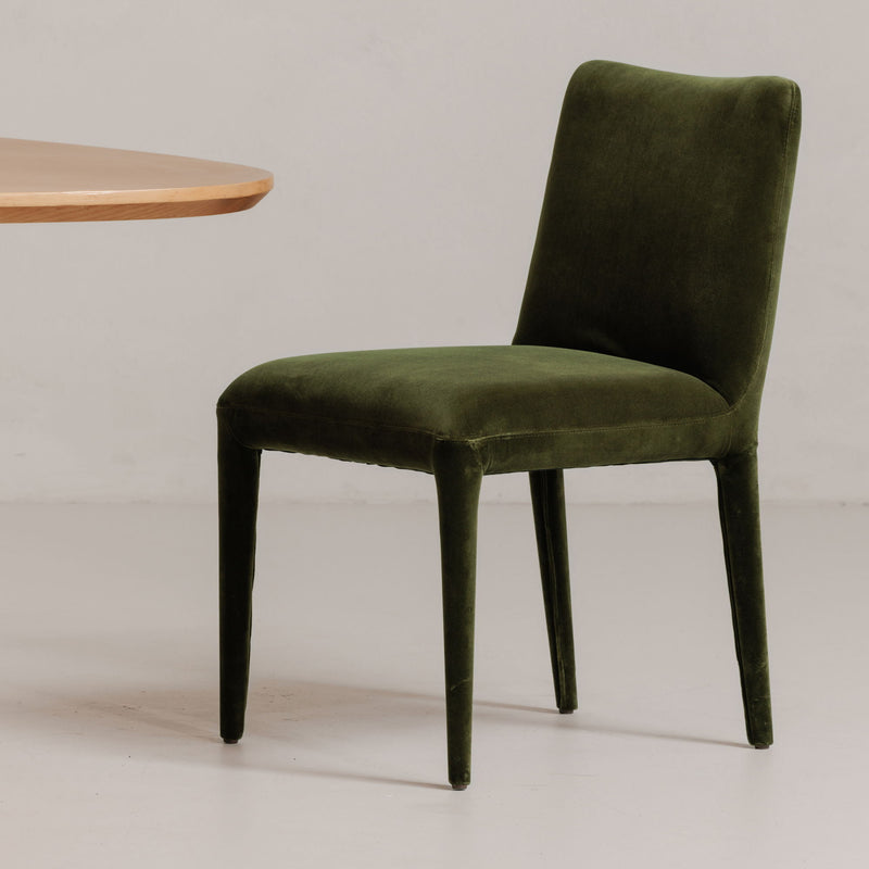Green velvet dining chair with tall square back, padded seat, tapered legs