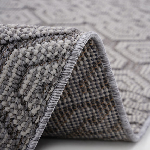 Gray-and-white geometric area rug close-up of textured loop pile and braided edge