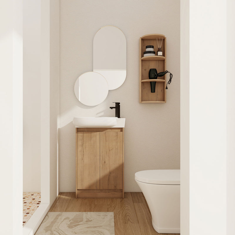 Light wood freestanding bathroom vanity with oval sink and two cabinet doors, plus wall storage