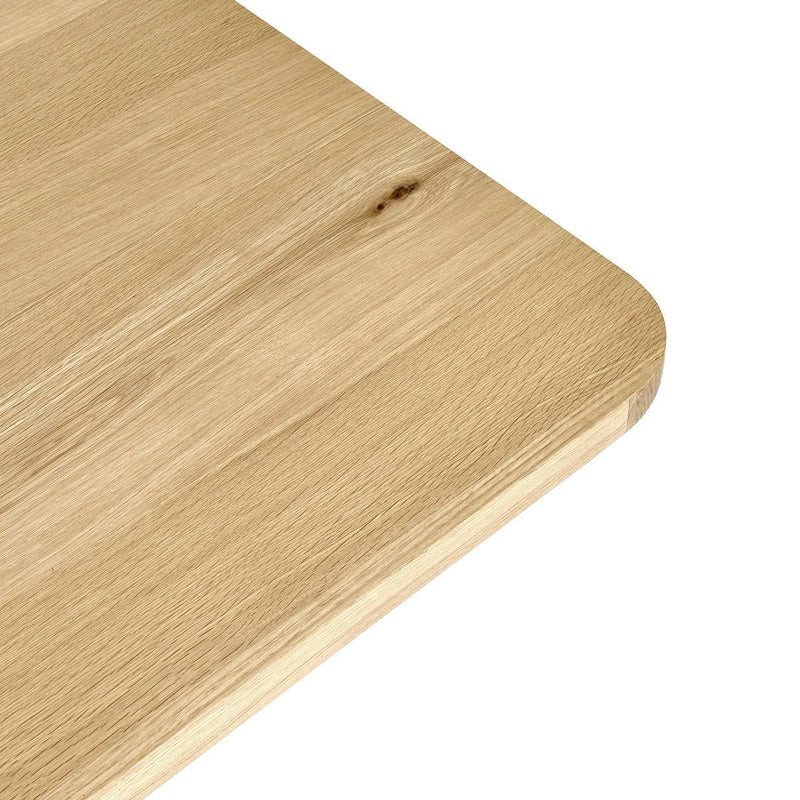 Light wood dining table with rounded corner edge detail and visible grain