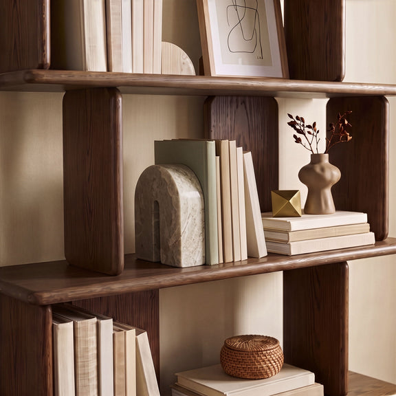 Beige marble bookend with arched cutout, shown on bookshelf