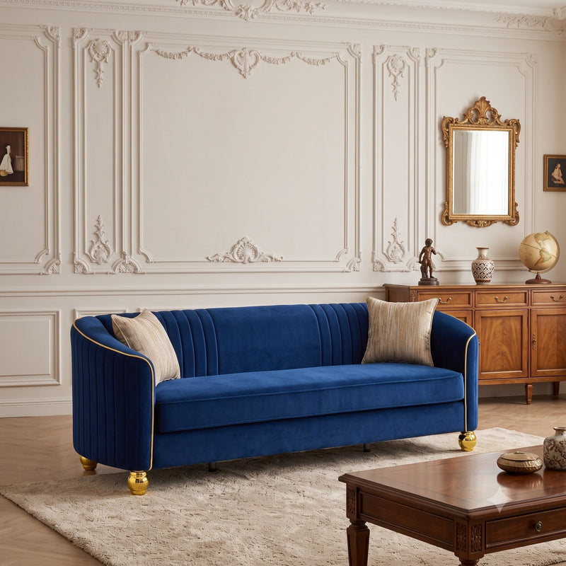 Navy three-seat sofa with gold piping, fluted back, gold feet, and two beige accent pillows