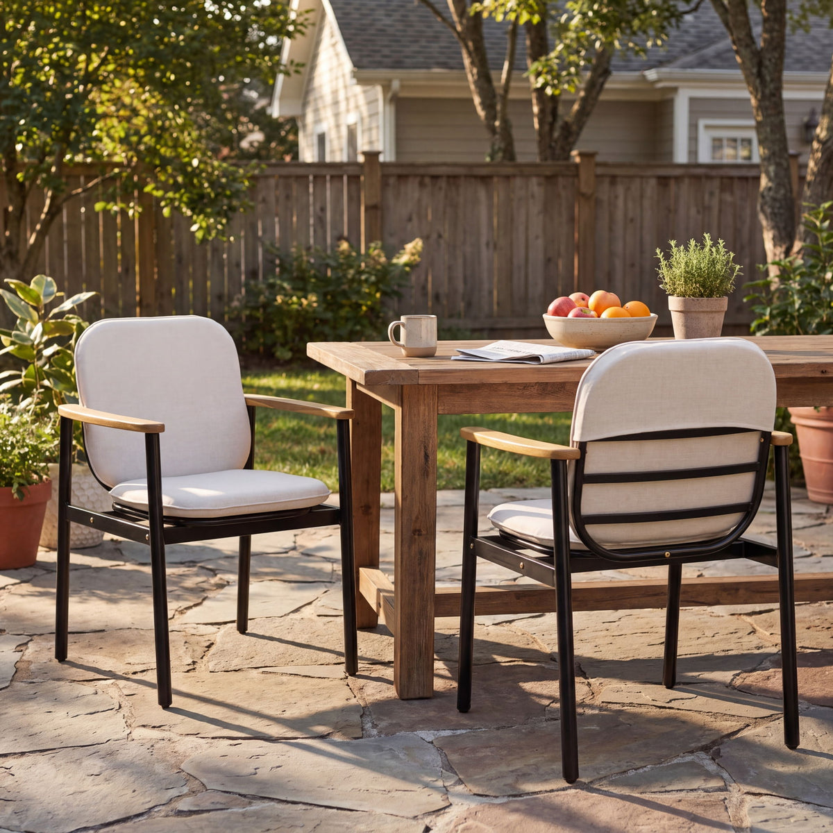Set of two beige outdoor dining chairs with black frames and teak armrests