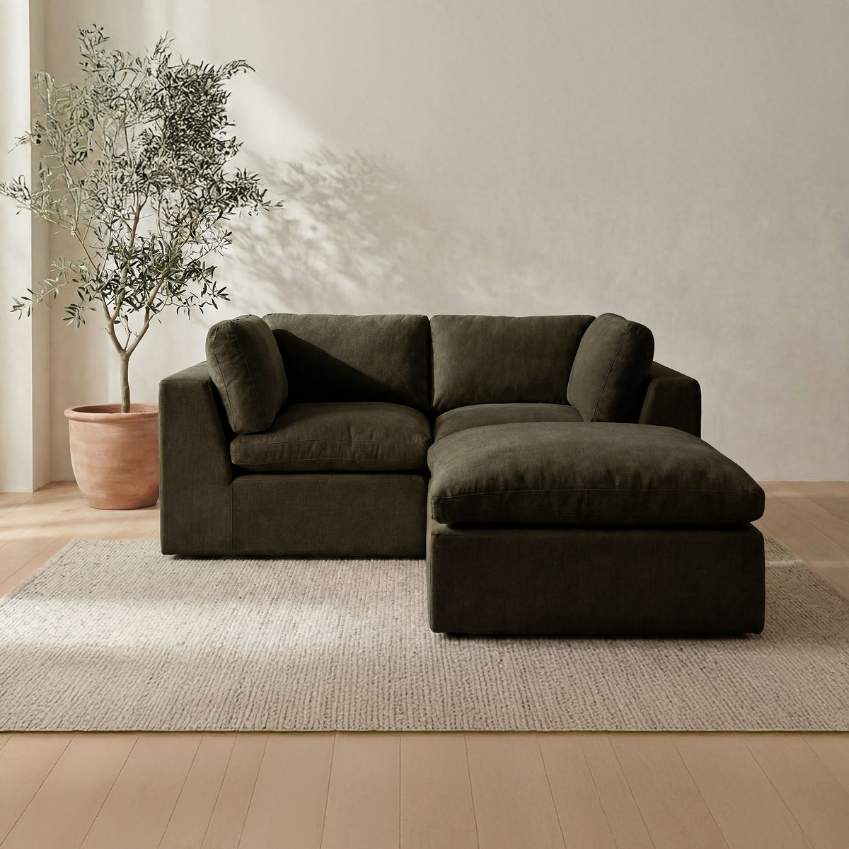 Dark green modular sectional sofa with chaise, plush seat cushions in L-shape