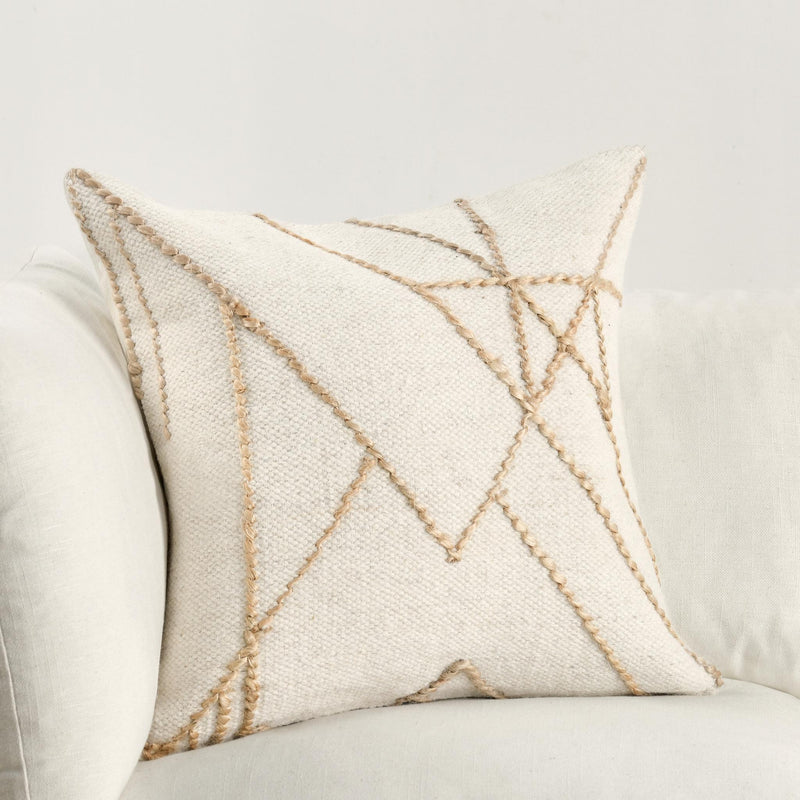 Ivory decorative pillow on sofa, natural tan embroidered geometric line pattern