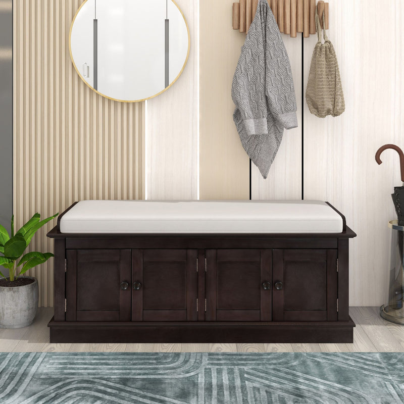 Dark brown shoe bench with a white cushion and four storage doors